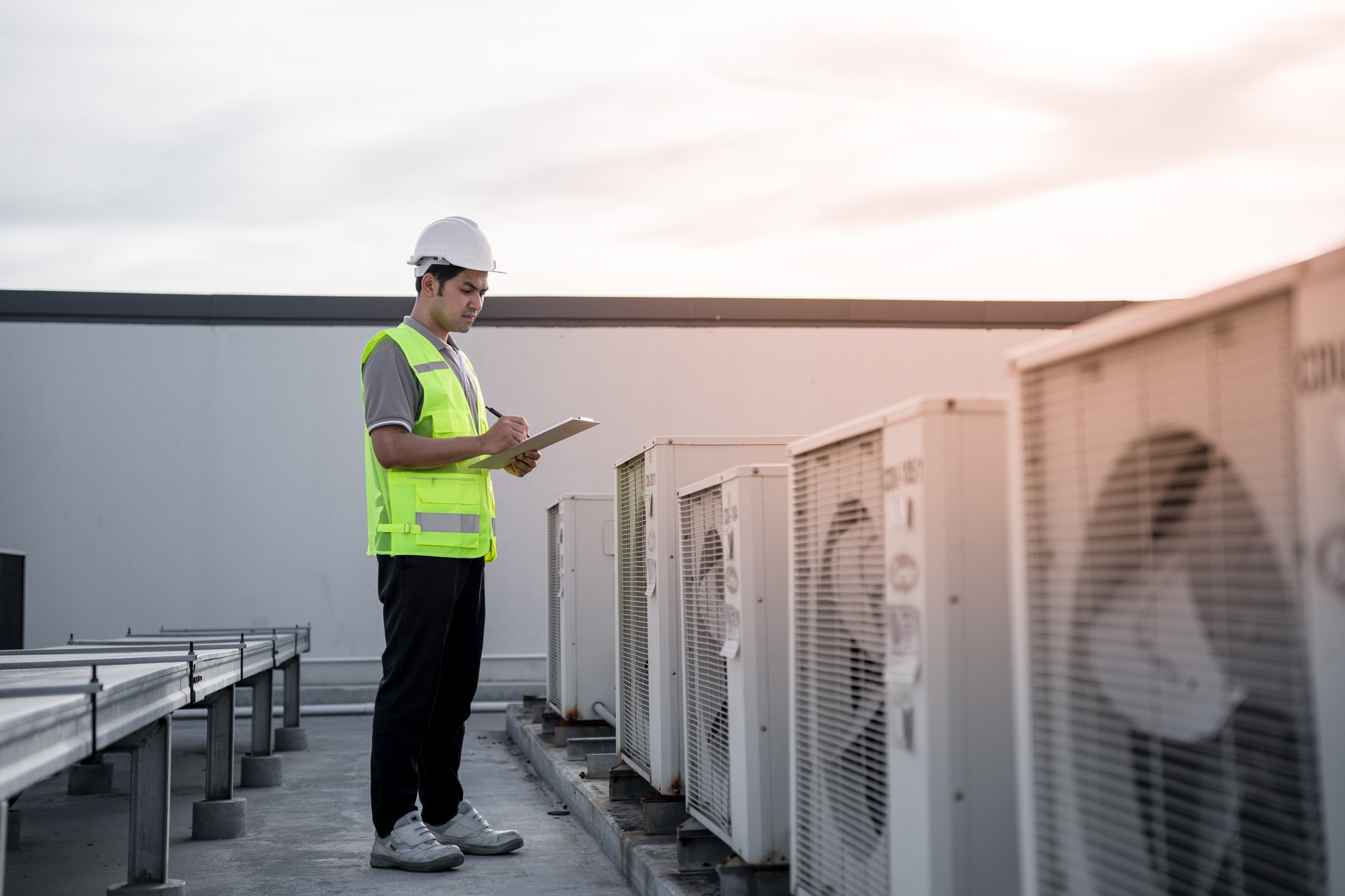 Factory engineers walking and checking the cooling system of the factory. Fore man records the condition of the compressor before maintenance according maintenance plan.